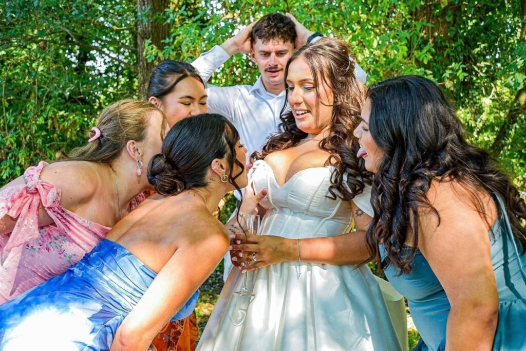 Bride hugged by her bridesmaids in colorful dresses in a garden