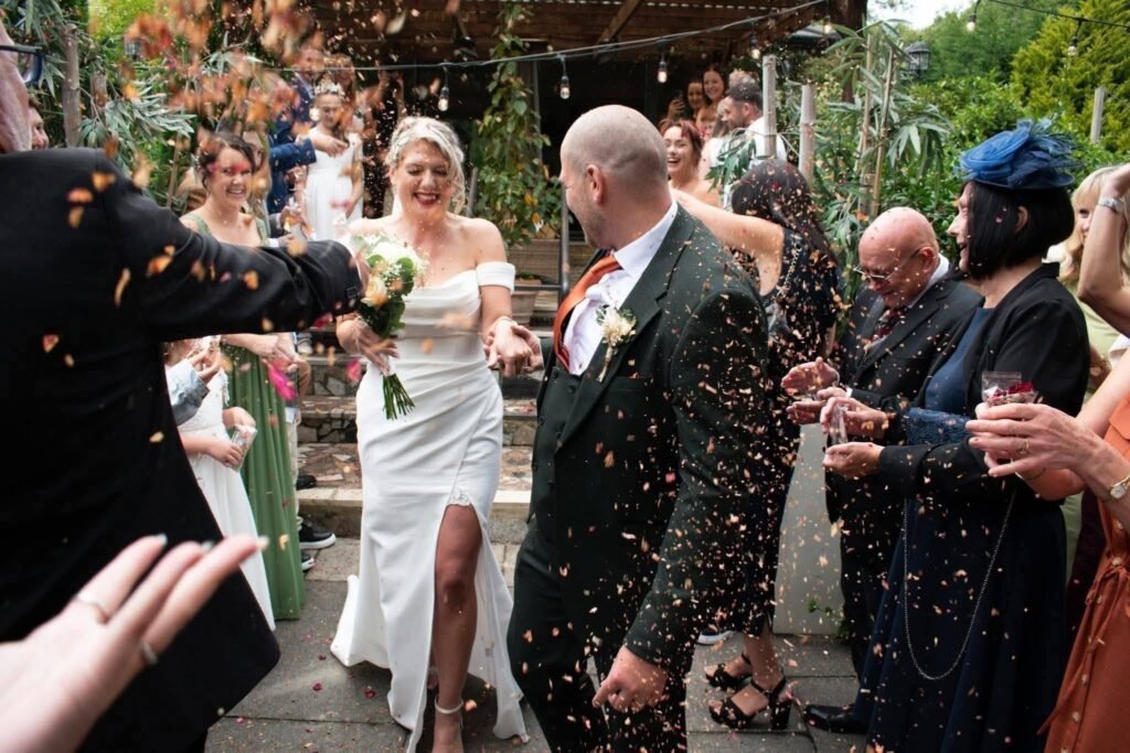 Bride and groom walking out through a confetti toss from guests