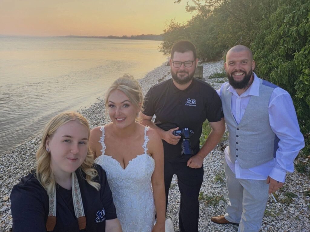 Bride with guests on a pebble beach at sunset