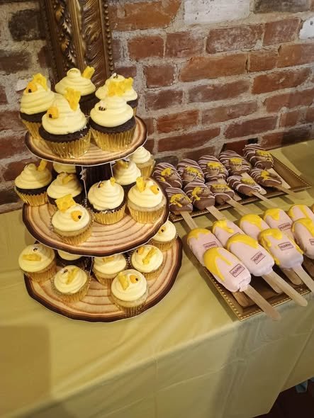 Honey bee cupcakes on a wood slice stand next to pink and yellow Winnie the Pooh cakesicles