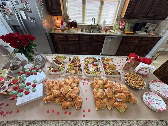 Baby shower food table with sandwiches, apples and red roses on a kitchen counter