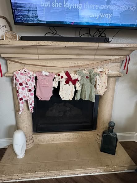Clothesline of baby onesies hanging on a fireplace at a baby shower