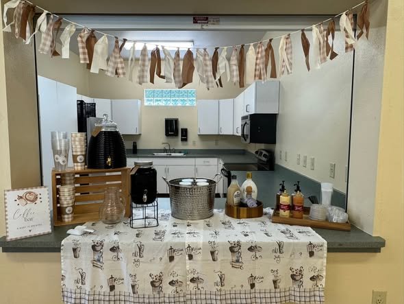 Baby shower coffee bar with a fabric banner, coffee pots and cups