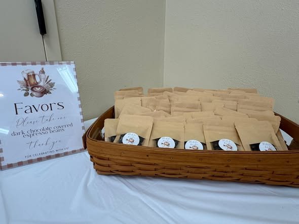Coffee bag favors in a basket with a favors sign