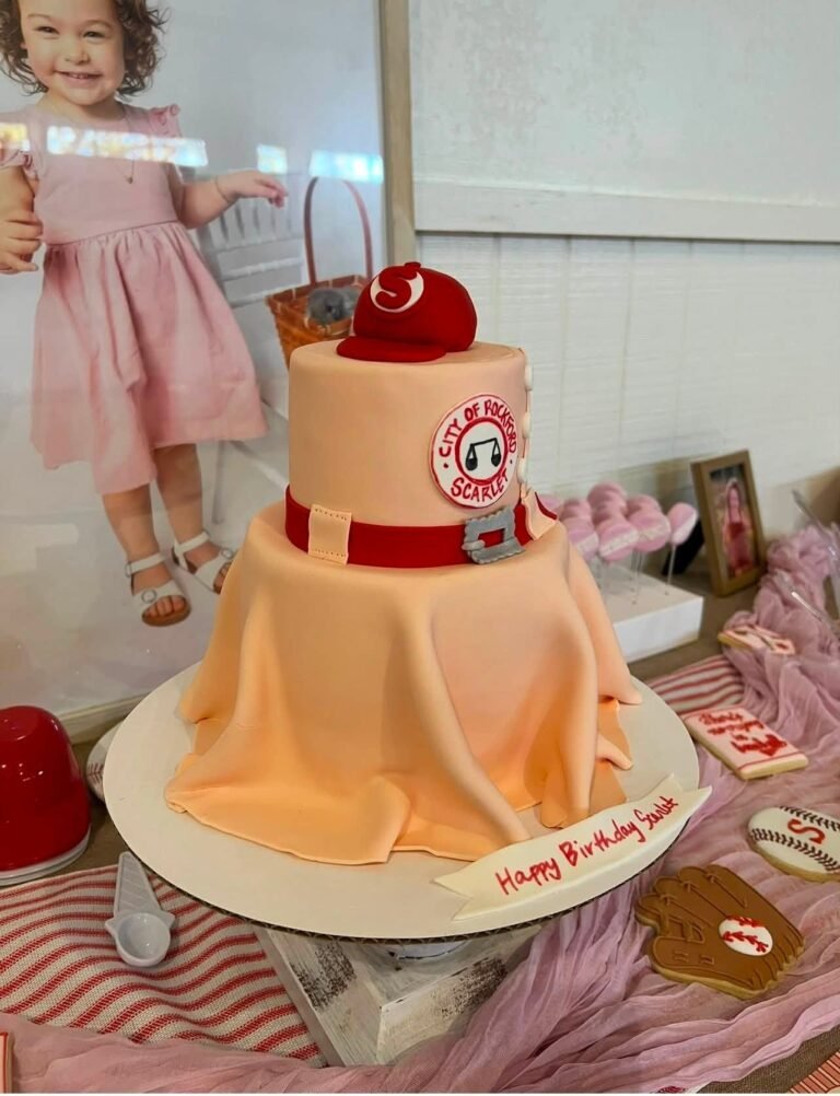 Peach fondant baseball cake with red stitching and a red cap on top