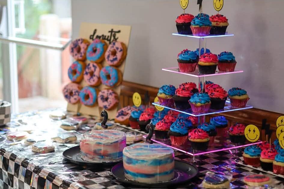 Rock theme dessert table with a donut wall, cupcake tower and smiley face decor