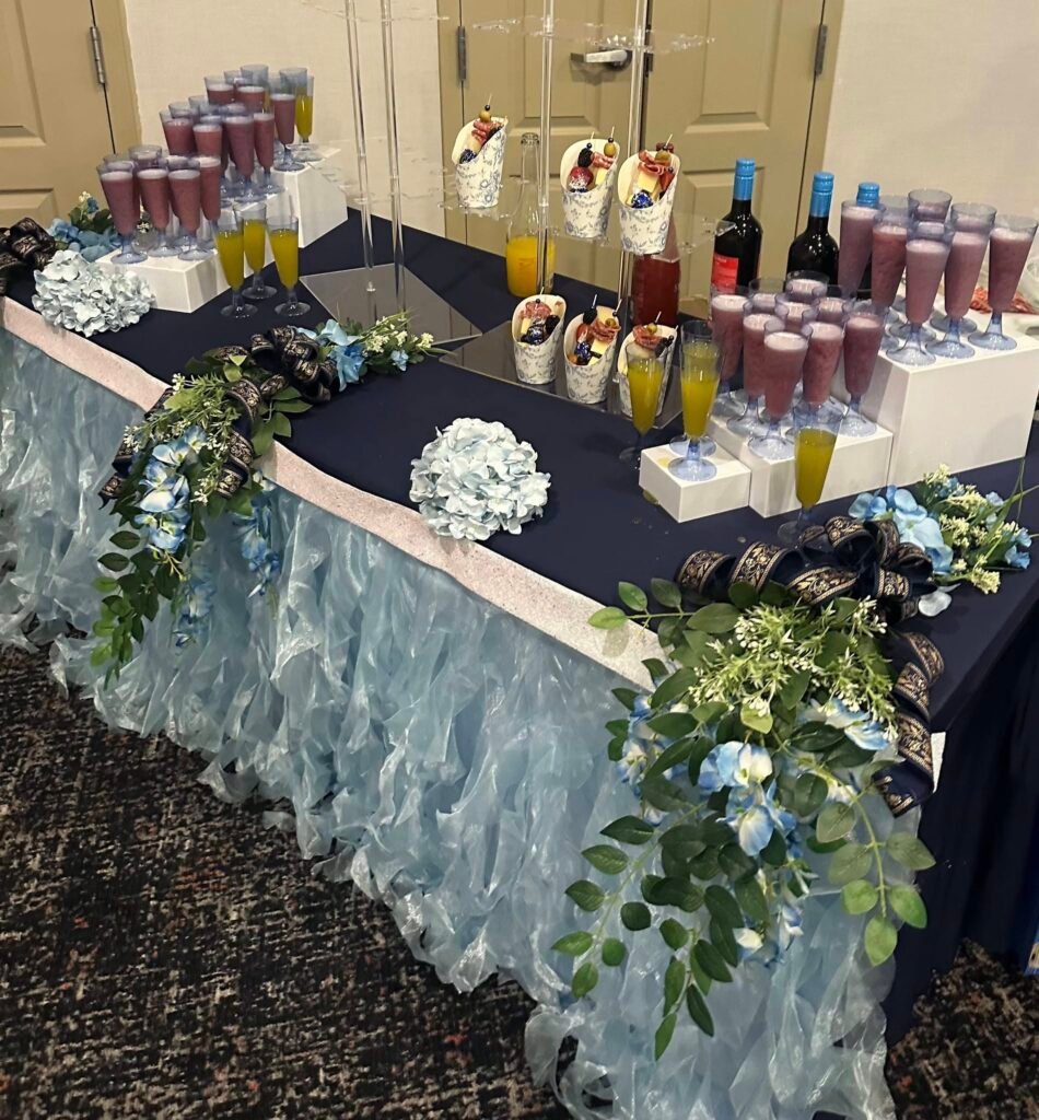 Graduation drink and dessert table with a blue ruffle skirt and greenery