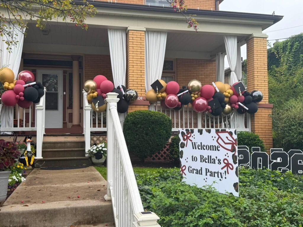 Porch with a maroon, gold and black balloon garland and a grad party welcome sign