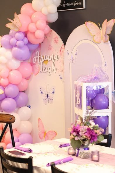 Pink and lilac balloon garland with a white butterfly arch at a baby shower