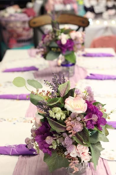 Purple and pink flower centerpiece on a lilac runner with purple napkins