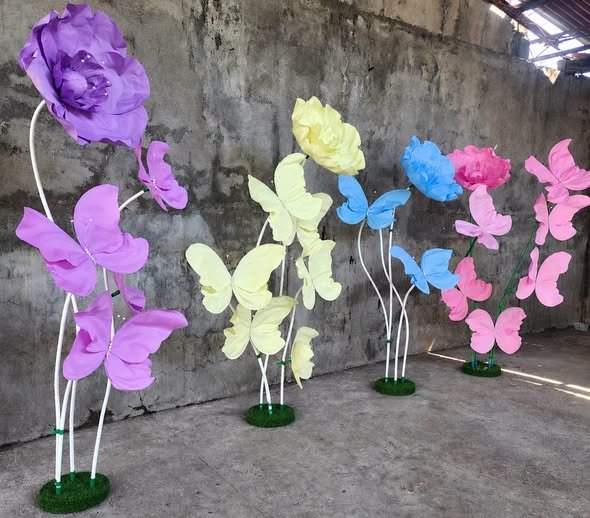 Giant paper butterfly and flower stands in purple, yellow, blue and pink