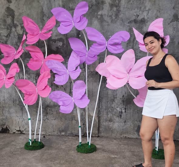 Pink and lilac giant paper butterfly stands with a guest posing