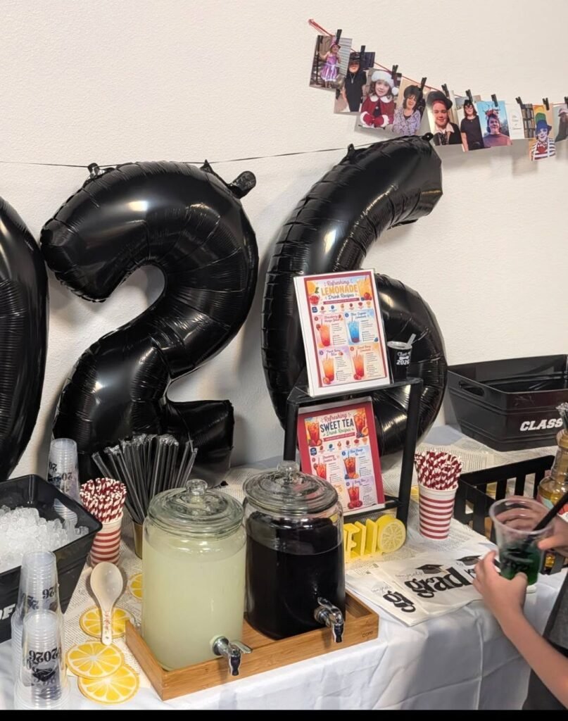 Black 2026 balloons next to a lemonade station and a line of photos