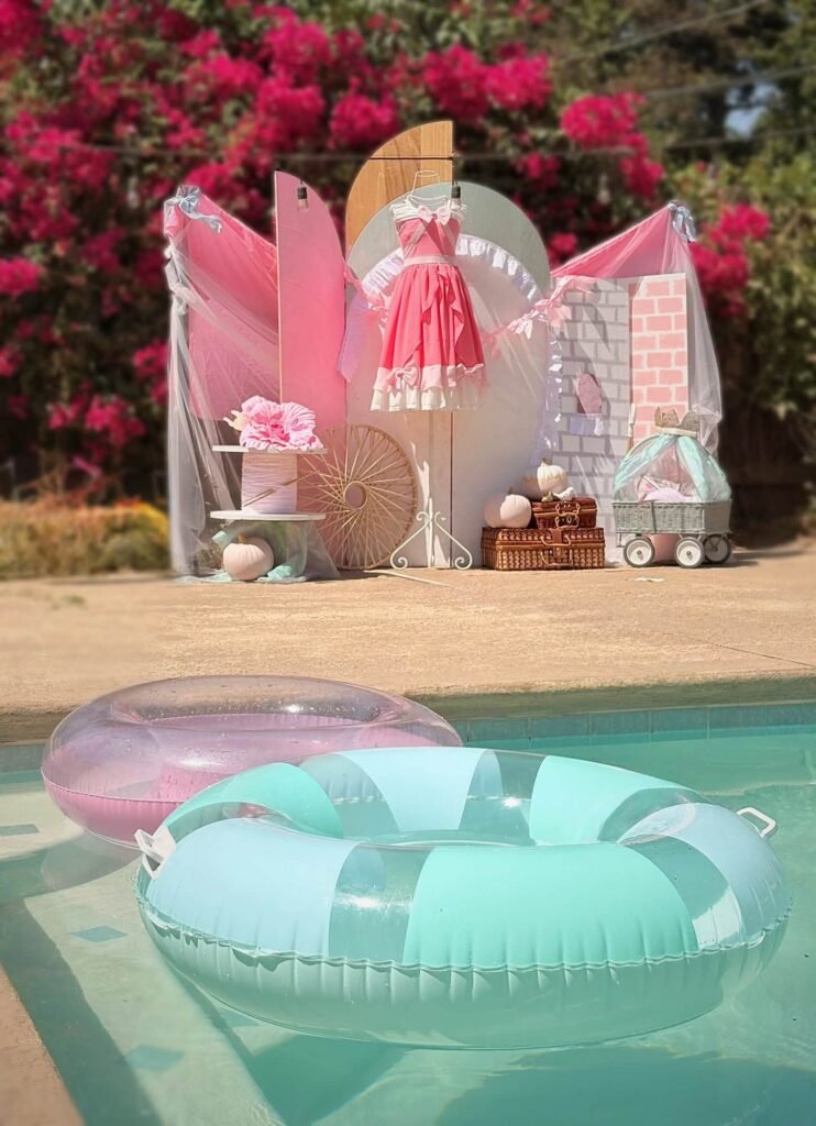 Poolside Cinderella party setup with a pink dress display and a blue pool float