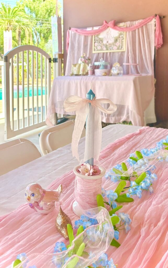 Pink Cinderella party table with a pink runner, blue flowers and a castle at the end