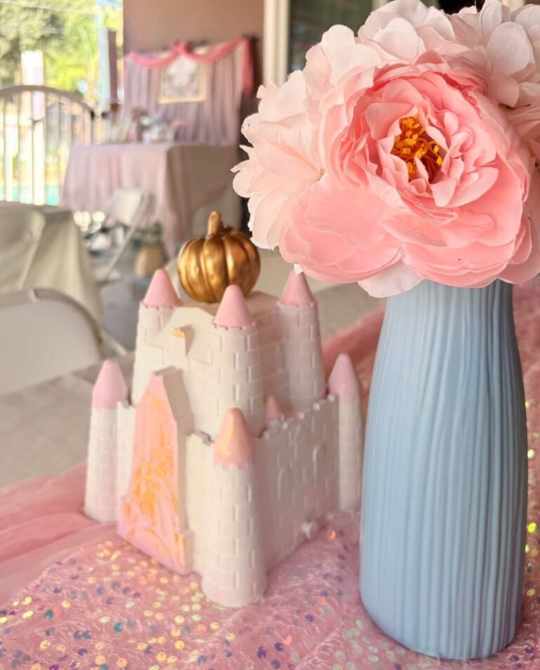 Cinderella castle centerpiece with a pink peony and a blue vase on a glitter table