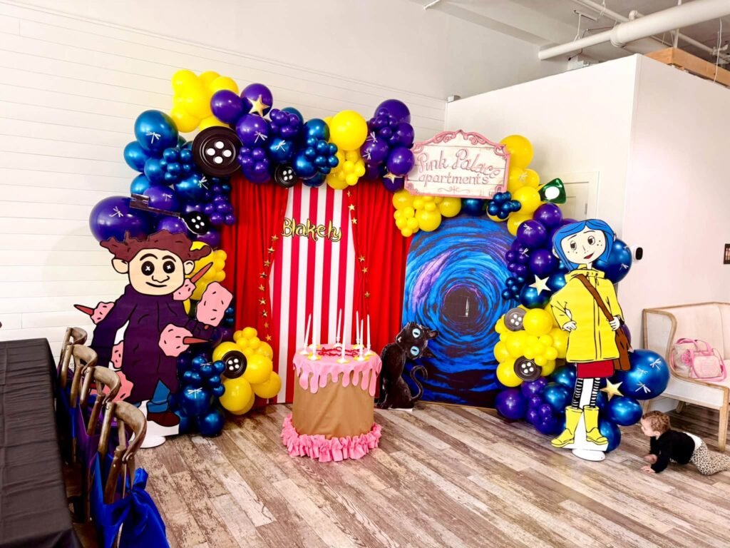 Colorful balloon backdrop with a Coraline sign and popcorn box decor