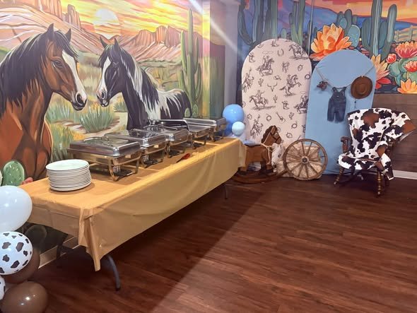Western baby shower buffet with chafing dishes under a horse mural