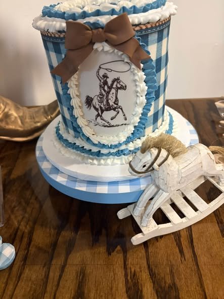 Blue gingham baby shower cake with a cowboy picture, brown bow and rocking horse