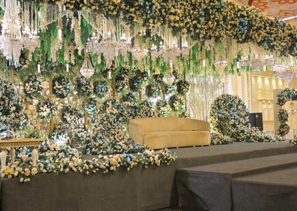 Wedding stage with a greenery and white flower ceiling and a gold sofa
