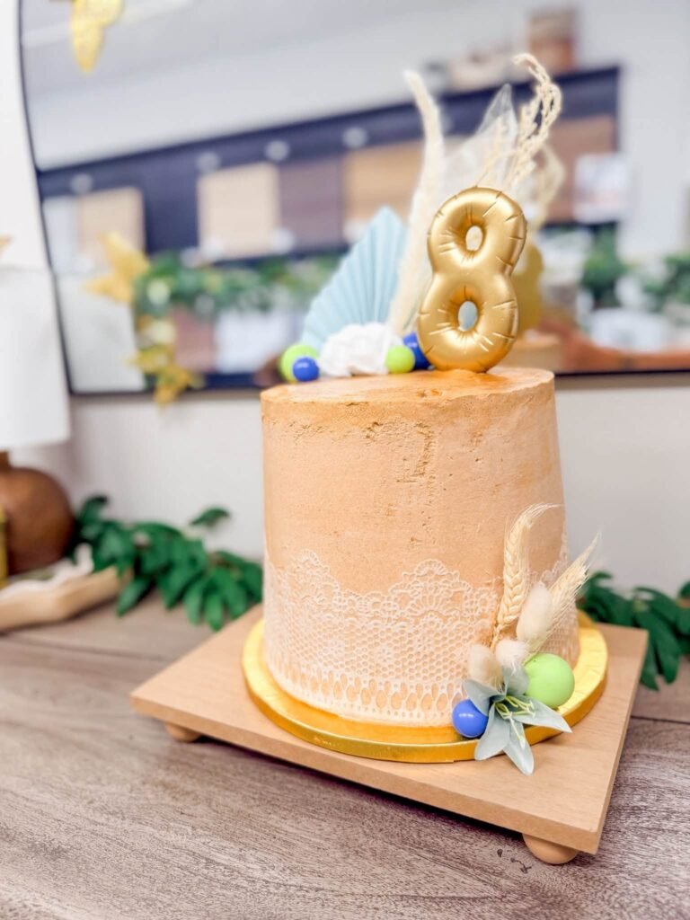 Neutral textured birthday cake with a gold number 8 and pampas grass
