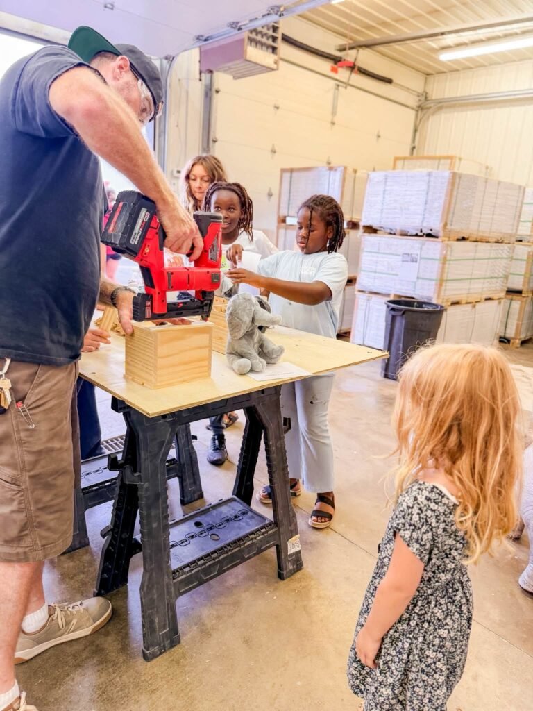 Kids building wood projects with an adult at a woodworking station
