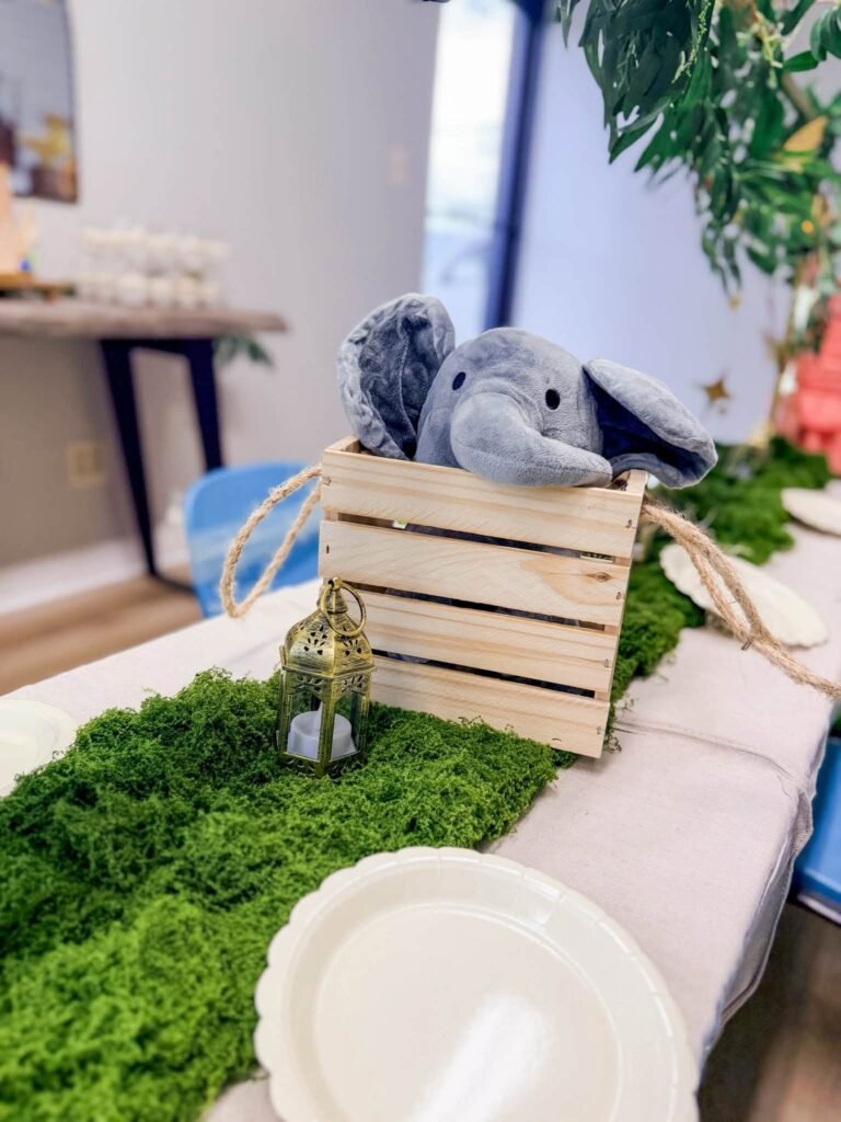 Plush elephant in a wood crate on a moss table runner