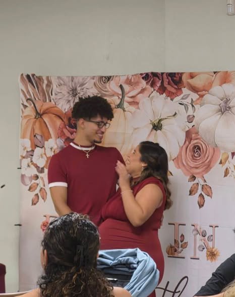Parents to be posing in front of a floral fall baby shower backdrop