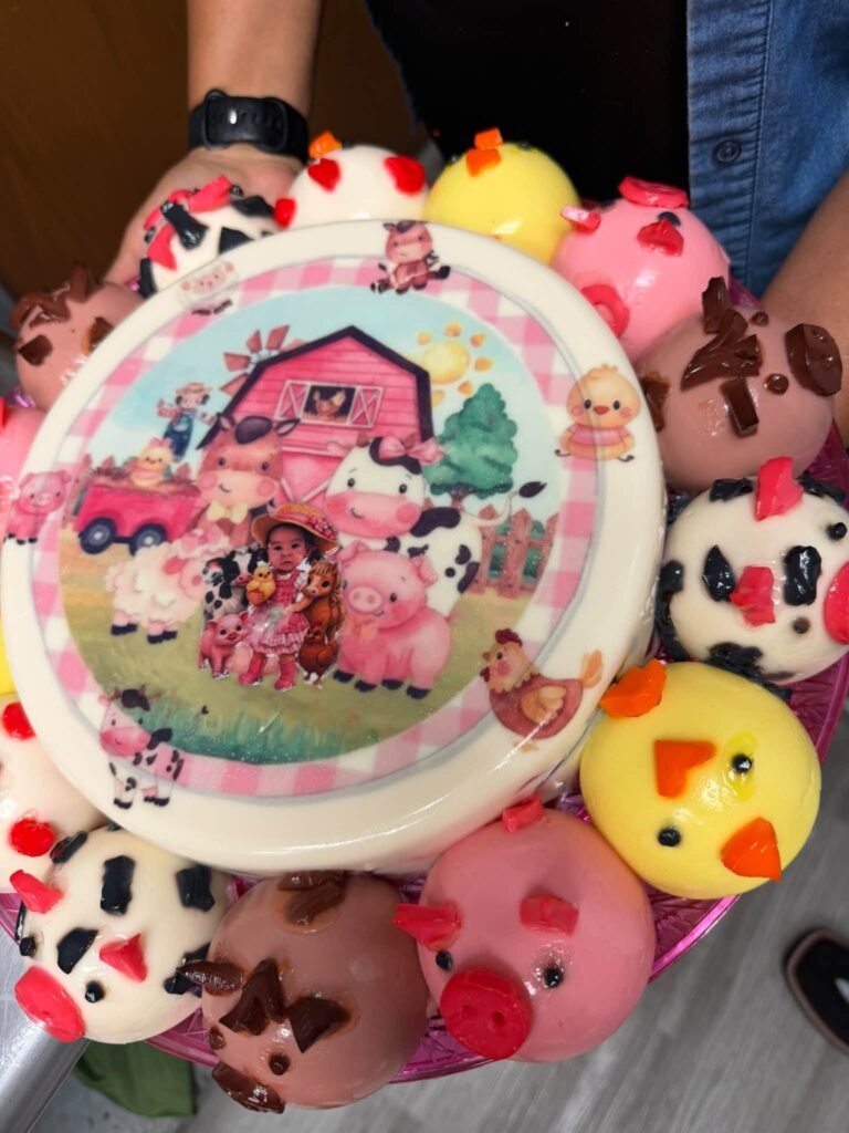 Pink farm cake with cow, pig and chick cookies around it