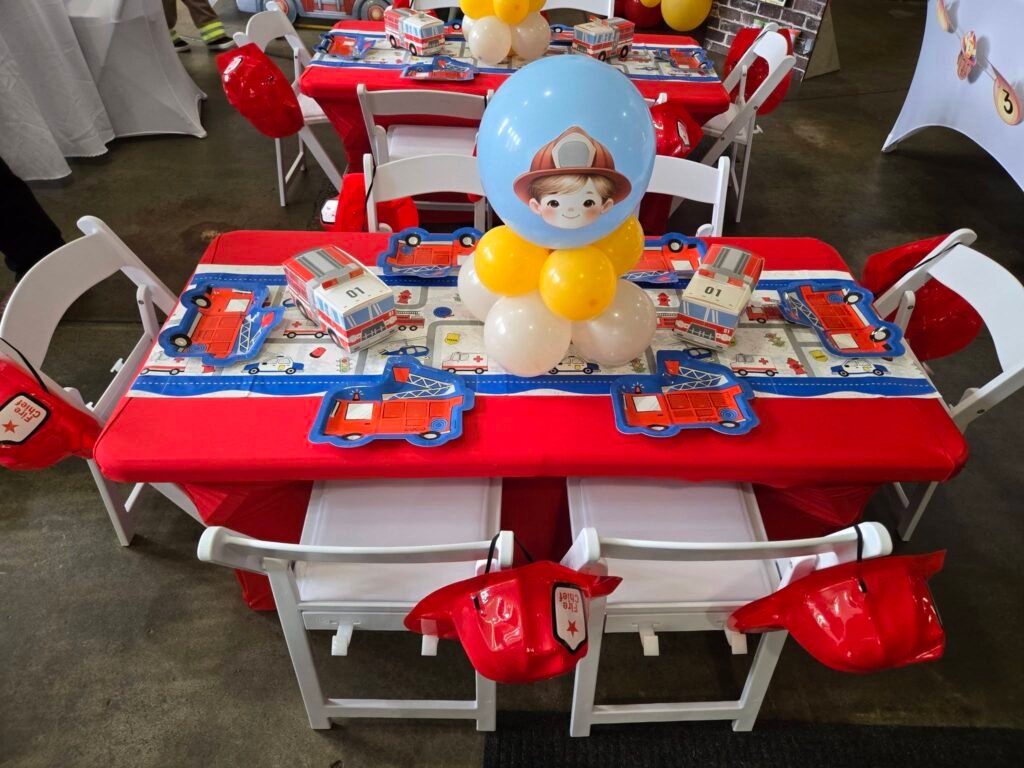 Kids table with red cloth, red fire hats and a balloon centerpiece