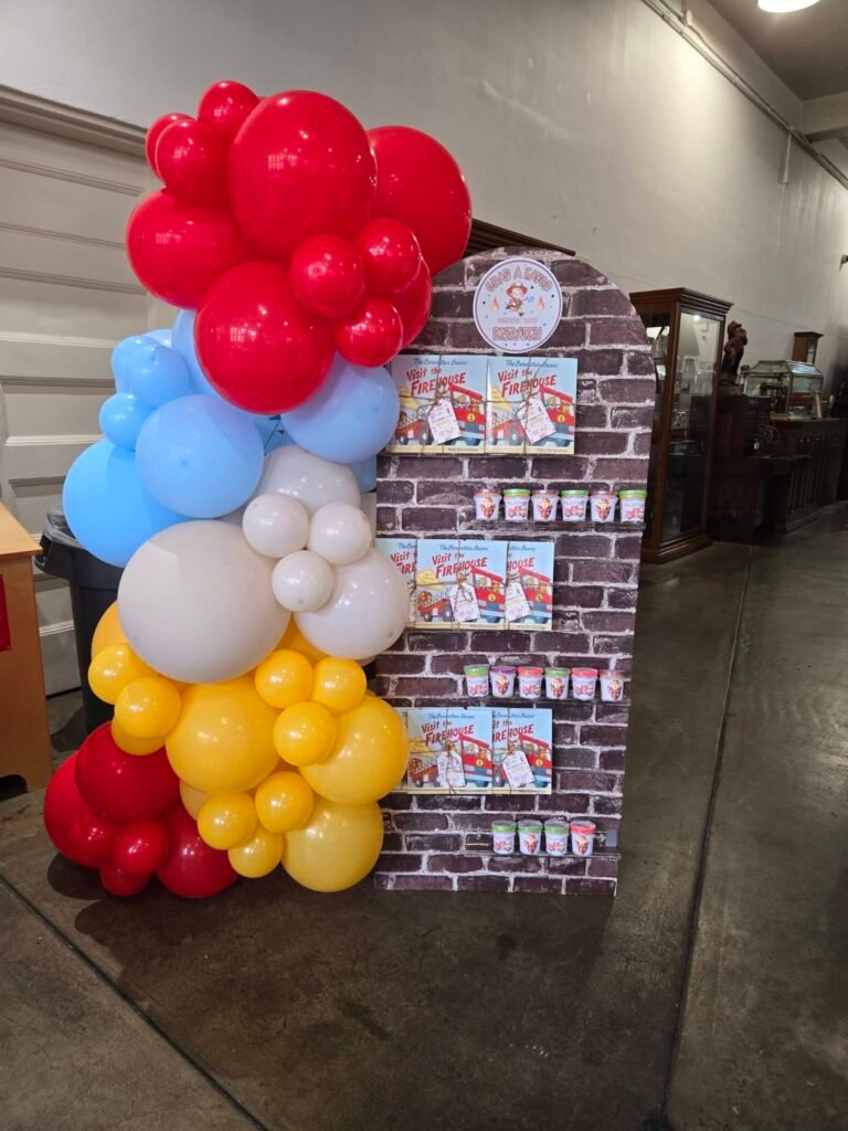 Red, blue, white and yellow balloon column next to a brick wall sign