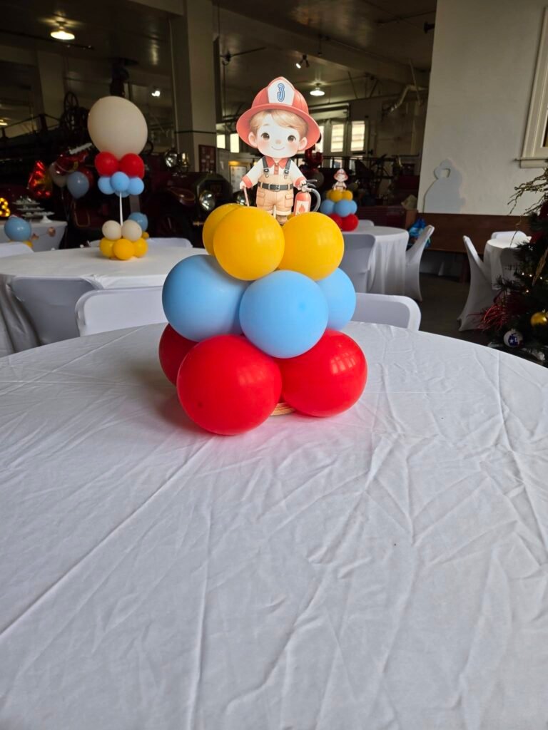 Balloon centerpiece with a firefighter kid cutout on a white table