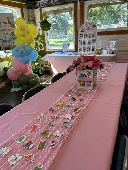 Long pink party table with a book page runner and a floral book centerpiece