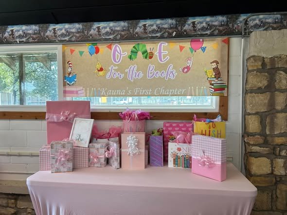 One for the Books gift table with a banner and pink gift bags
