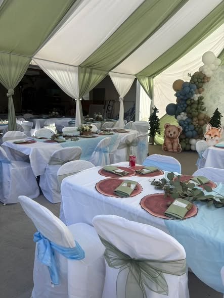 Tent baby shower tables with white covers, sage napkins and greenery