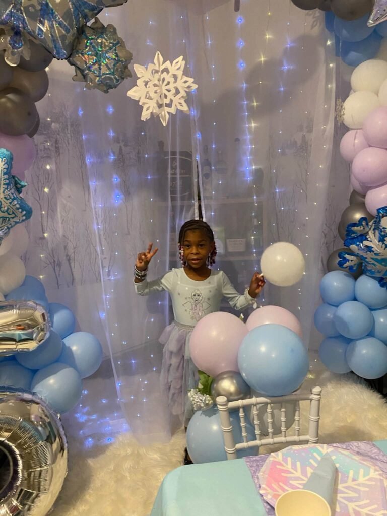 Girl posing at a Frozen photo spot with snowflakes and icy balloons