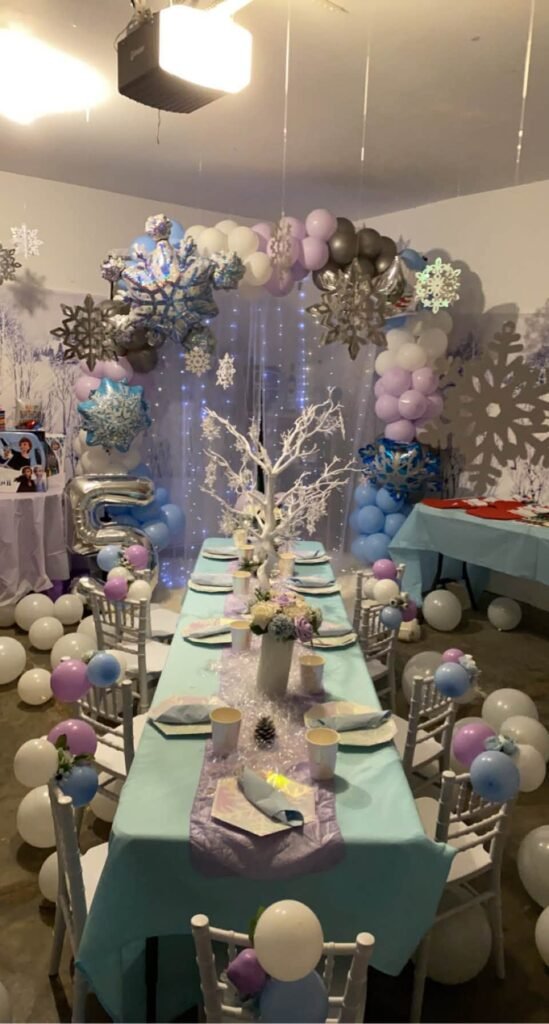 Long Frozen birthday table with blue runners, silver chargers and balloons