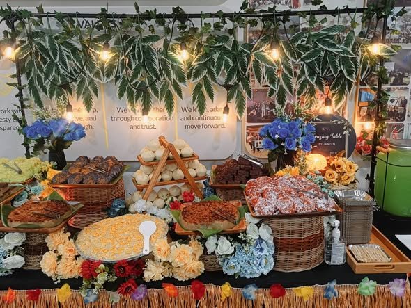 Long grazing table with pastries, breads and blue and orange flowers under string lights
