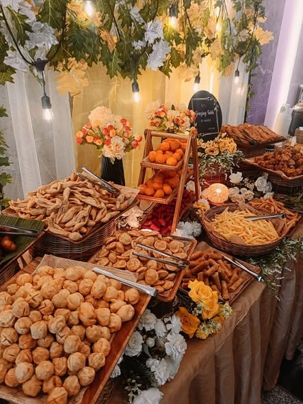 Close up of baskets of bread rolls, fries and fruit with flowers on a grazing table