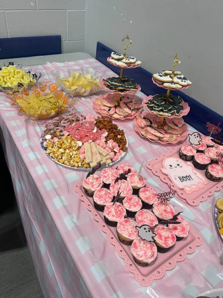 Pink gingham dessert table with cupcakes, snacks and cookies
