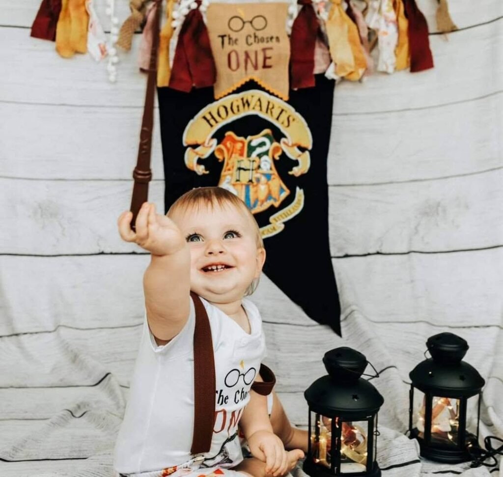 Baby reaching up under a Hogwarts banner with lanterns