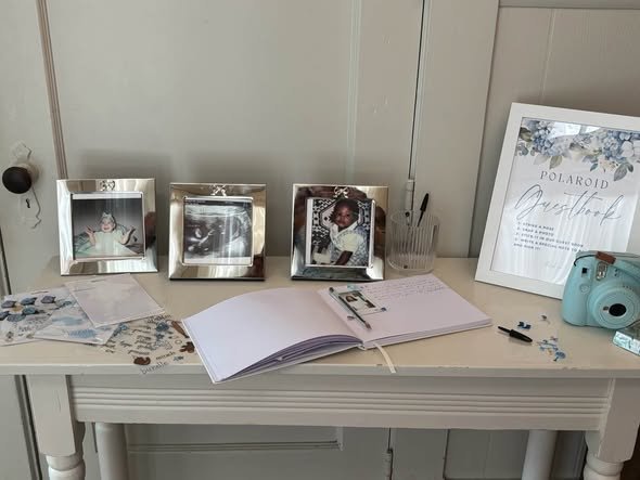 Baby shower guest book table with silver photo frames and an instant camera