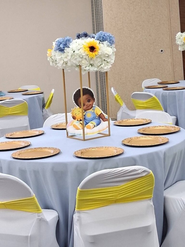 Round table with gold chargers, yellow sashes and a tall flower centerpiece