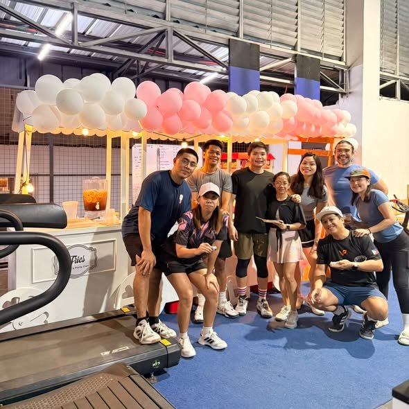 Group of guests posing by white food carts with a pink and white balloon canopy