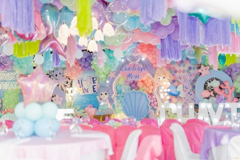 Pastel mermaid birthday stage with shells and soft blue balloons