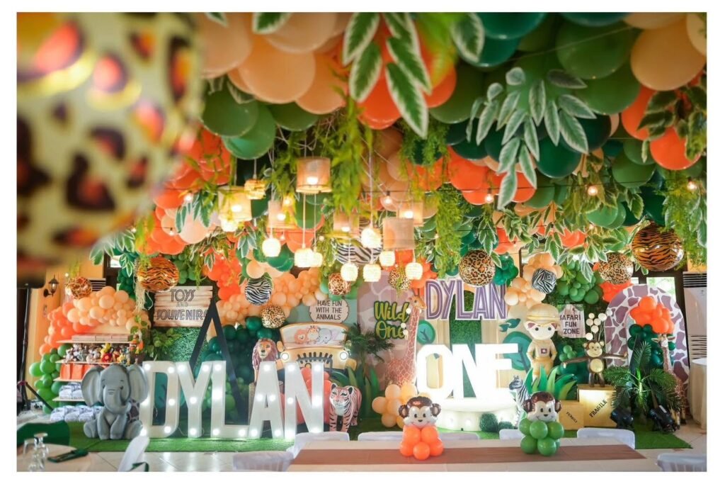 Jungle ONE first birthday stage with leopard print, greenery and orange balloons