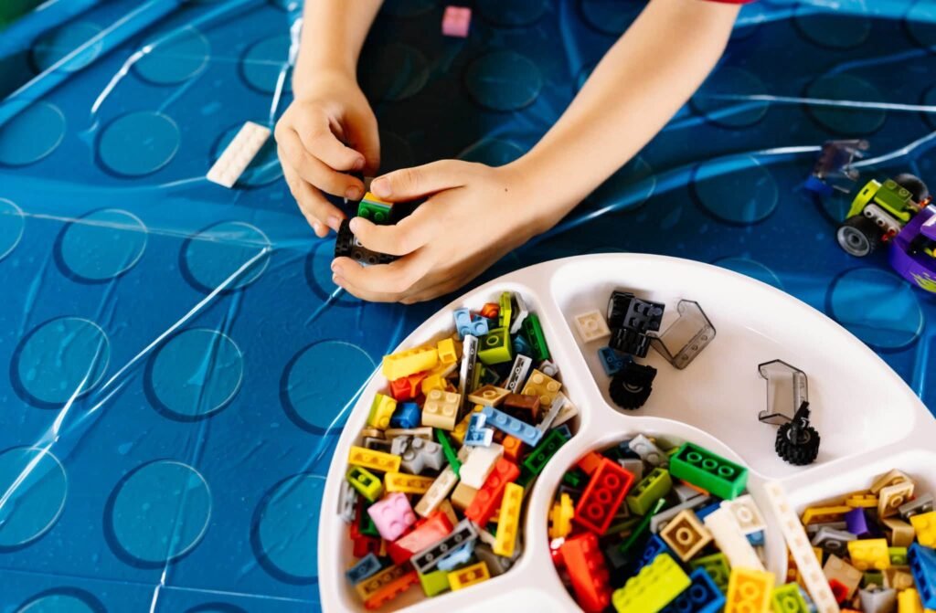 Kids building with LEGO bricks from a white sectioned tray