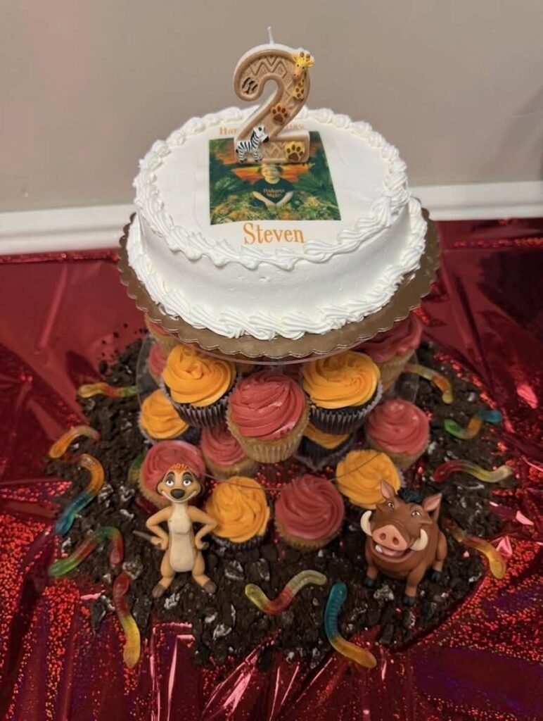 Lion King cake on a stand with chocolate cupcakes around it
