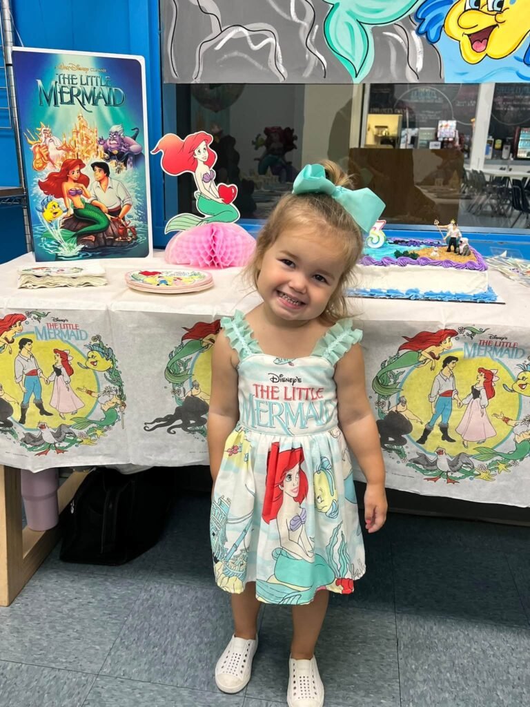 Little girl in a mermaid dress by the party table