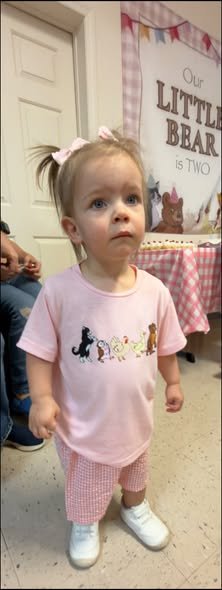Birthday girl in a pink Little Bear shirt and shorts set with a bow in her hair